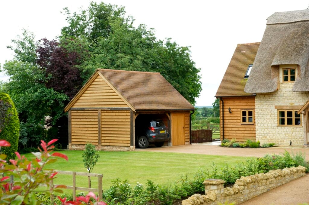 oak frame 2 bay garage with car and  oak frame cottage and garden