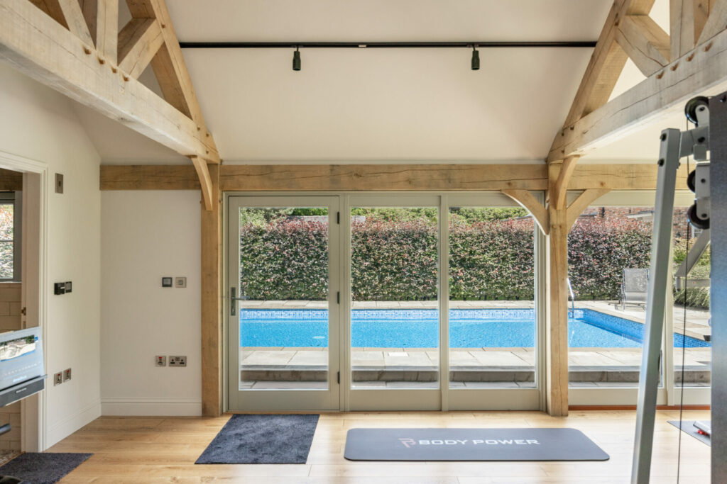 Home gym with wall of windows and swimming pool outside