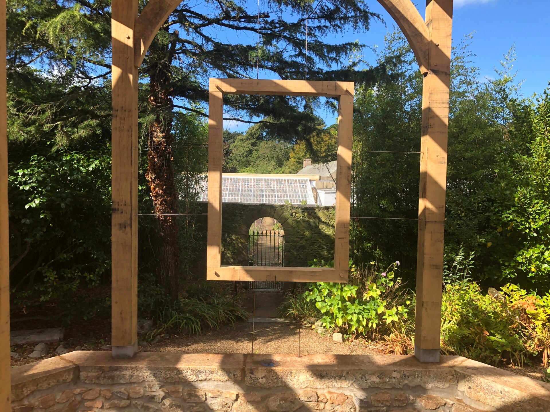 Pergola in garden with glasshouse in distance